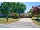 Charming brick home with a well-manicured lawn, mature trees, and a paved driveway under a blue sky at 779 Dills Bluff Rd, Charleston, SC 29412