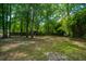 Shady backyard with mature trees, grass, and a glimpse of the surrounding neighborhood at 100 Colonial Dr, Goose Creek, SC 29445
