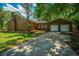 Brick home with attached garage and paved driveway surrounded by mature trees and lush landscaping at 100 Colonial Dr, Goose Creek, SC 29445
