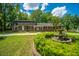 Charming brick home with well-manicured lawn, mature trees, and inviting water fountain at 100 Colonial Dr, Goose Creek, SC 29445