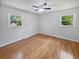 Minimalist bedroom with hardwood floors, two large windows, and a ceiling fan, offering a blank canvas for personalization at 102 Rebellion Rd, Summerville, SC 29483