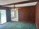 Living room with wood paneled walls, green carpet, ceiling fan, and sliding glass doors to the backyard at 104 Belmont Ct, Ladson, SC 29456