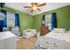 This bedroom features green walls, light-colored wood floors, two windows, and two beds with colorful bedspreads at 104 Greensboro Ln, Ladson, SC 29456