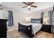 A well-lit bedroom featuring a dark bed frame, ceiling fan and wood-look floors at 104 Greensboro Ln, Ladson, SC 29456