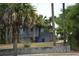 Cozy blue home surrounded by lush palm trees and a charming block wall in the front yard at 1106 Palmetto Blvd, Edisto Island, SC 29438