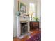 Close-up of a fireplace with vintage screen, mantle decorated with urn and pheasant decor and beautiful floors at 15 Rutledge Ave, Charleston, SC 29401