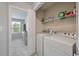 Laundry room with appliances, storage shelf, and a door leading to a well-lit room with view at 1589 Bluewater Way, Charleston, SC 29414