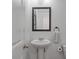 A clean powder room with pedestal sink, framed mirror and a neutral color palette at 1589 Bluewater Way, Charleston, SC 29414