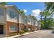 Exterior view of townhomes with brick accents, manicured lawn, blue sky, and mature trees at 241 Howle Ave # F, Charleston, SC 29412