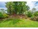 Landscaped backyard with lush grass, mature trees, and a charming black fence at 2596 Hatch Dr, Johns Island, SC 29455