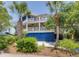 Charming coastal home featuring double balconies, a blue garage, and tropical landscaping at 3009 Palm Blvd, Isle of Palms, SC 29451