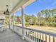Inviting covered porch with white railings, ceiling fan, and views of the surrounding landscape at 3381 Stockdale St, Mount Pleasant, SC 29466