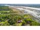 Aerial view of a riverfront property surrounded by beautiful trees, marshlands, and a long dock at 3399 Freeman Hill Rd, Johns Island, SC 29455