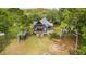 Aerial view of the two-story home, showcasing its surrounding greenery, front porch, and a detached shed at 3399 Freeman Hill Rd, Johns Island, SC 29455