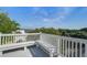 An inviting outdoor balcony features a white bench overlooking lush trees and a bright blue sky at 413 Station 22 1/2 St, Sullivans Island, SC 29482