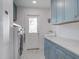 Well-lit laundry room with light blue cabinets, marbled countertops, and modern washer and dryer units at 413 Station 22 1/2 St, Sullivans Island, SC 29482