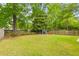 Large, grassy backyard with mature trees, a wooden fence and a storage shed at 4524 Orr St, North Charleston, SC 29405