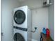 Modern laundry room with a stackable washer and dryer, wire shelving, and white walls at 754 Certificate Ct, Charleston, SC 29414