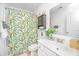 Bright bathroom with tropical curtain, vanity with white cabinets, and a leafy plant at 78 Branch Creek Trl, Summerville, SC 29483