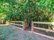 View of a wooden fence with a gate, surrounded by lush greenery, enclosing the backyard at 8035 Mckayla Rd, Summerville, SC 29483