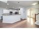 Open-concept layout with white kitchen cabinets, gray countertops, and hardwood flooring at 8035 Mckayla Rd, Summerville, SC 29483