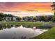 Scenic pond reflecting townhomes under a colorful sunset sky, with lush green surroundings at 822 Rue Dr, Charleston, SC 29414