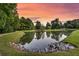 Scenic pond reflecting trees under a colorful sunset sky, with lush green surroundings at 822 Rue Dr, Charleston, SC 29414