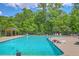 Large community pool surrounded by mature trees, lounge chairs, and sunbathing guests at 8632 Madelyn St, North Charleston, SC 29406