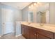 Bathroom with double sink vanity with dark wood cabinets, two mirrors, and a door to the WC at 9418 Sweep Dr, Summerville, SC 29485
