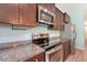 Kitchen showcasing stainless steel appliances, granite countertops, and stylish dark wood cabinets, offering a modern cooking space at 9418 Sweep Dr, Summerville, SC 29485