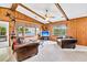 Spacious living room with beamed ceiling, wood paneled walls, and a view to the screened in porch at 107 Jacks Ln, Bonneau, SC 29431