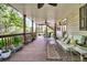 Spacious covered porch with wooden floors and plush seating, overlooking the serene wooded backyard at 107 Jacks Ln, Bonneau, SC 29431