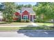 Red house with a manicured lawn, mature landscaping and inviting covered porch at 1126 Rearick Rd, Johns Island, SC 29455