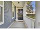 A welcoming front door features vinyl siding, white trim, a black door with wreath, and a covered porch at 117 Red Leaf Blvd, Moncks Corner, SC 29461