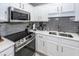 Close-up of a kitchen showcasing stainless steel appliances, gray subway tile, and white cabinets at 139 Spindle Way, Goose Creek, SC 29445