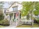 Charming two-story home with a welcoming front porch, American flag, and manicured landscaping at 1445 Lettered Olive Ln, Mount Pleasant, SC 29464