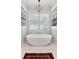 Bright bathroom boasts a modern tub centered beneath windows, flanked by shelving, and lit by a chandelier at 1474 Indian St, Mount Pleasant, SC 29464