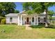 Charming home features a manicured lawn and covered porch with an inviting orange front door at 1474 Indian St, Mount Pleasant, SC 29464
