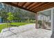 View of a spacious backyard with a paved patio, screened-in porch, lush lawn, and a wooded area, perfect for outdoor living at 176 Clearblue Loop, Summerville, SC 29486