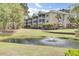 View of multi-story building with balconies overlooking a serene pond with a fountain and manicured lawn at 2014 Basildon Rd, Mount Pleasant, SC 29466