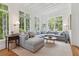 A spacious, light-filled living room features a large sectional sofa, wood floors and large windows overlooking the lush yard at 2158 Westrivers Rd, Charleston, SC 29412