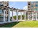 Beautiful courtyard featuring pergola with white columns, manicured lawn, and views of the bridge and buildings at 222 S Plaza Ct, Mount Pleasant, SC 29464