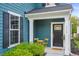 Inviting covered front porch with a seating area, lush landscaping, and a stylish black front door at 2324 Town Woods Rd, Charleston, SC 29414