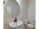 Modern half-bathroom features a stylish, round mirror, pedestal sink, and crisp white toilet at 239 Parkwood Vista Way, Summerville, SC 29486