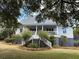 Traditional home with an inviting wide porch and staircase, set amidst lush landscaping and mature trees at 2624 Jenkins Point Rd, Seabrook Island, SC 29455