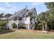 Charming coastal home with a welcoming front porch, lush landscaping, and mature palm trees at 2624 Jenkins Point Rd, Seabrook Island, SC 29455