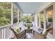 Cozy screened porch with wicker furniture, stylish rugs, and tranquil views of the surrounding trees at 2624 Jenkins Point Rd, Seabrook Island, SC 29455