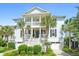 Inviting two-story home features dual garages, a double porch, palm trees, and manicured landscaping at 3101 S Shore Dr, Charleston, SC 29407