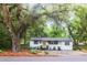 Quaint home surrounded by mature trees draped with Spanish moss, featuring a green door and fresh landscaping at 3293 River Rd, Johns Island, SC 29455