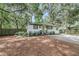 Charming home with a green front door and well-maintained landscaping, enhanced by gravel driveway and mature trees at 3293 River Rd, Johns Island, SC 29455